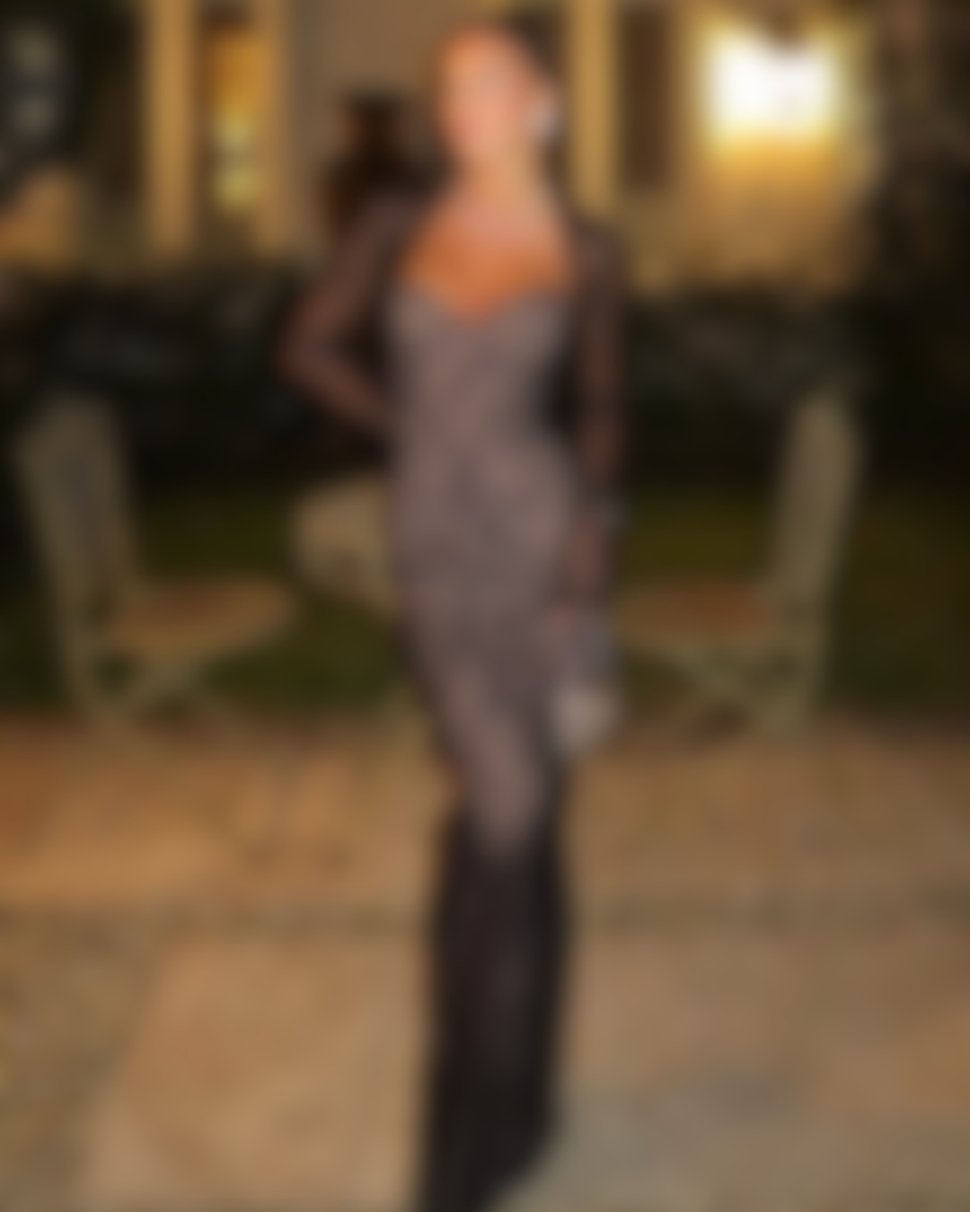 Women wearing a black lace night-out gown in a warm, evening setting.