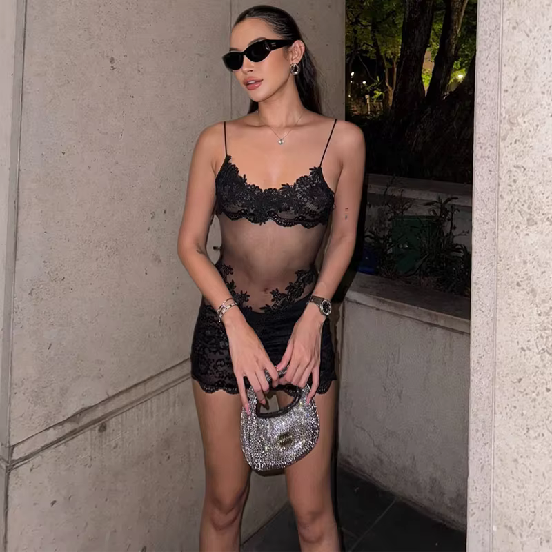 Model wearing sheer black lace mini dress in outdoor nighttime setting 