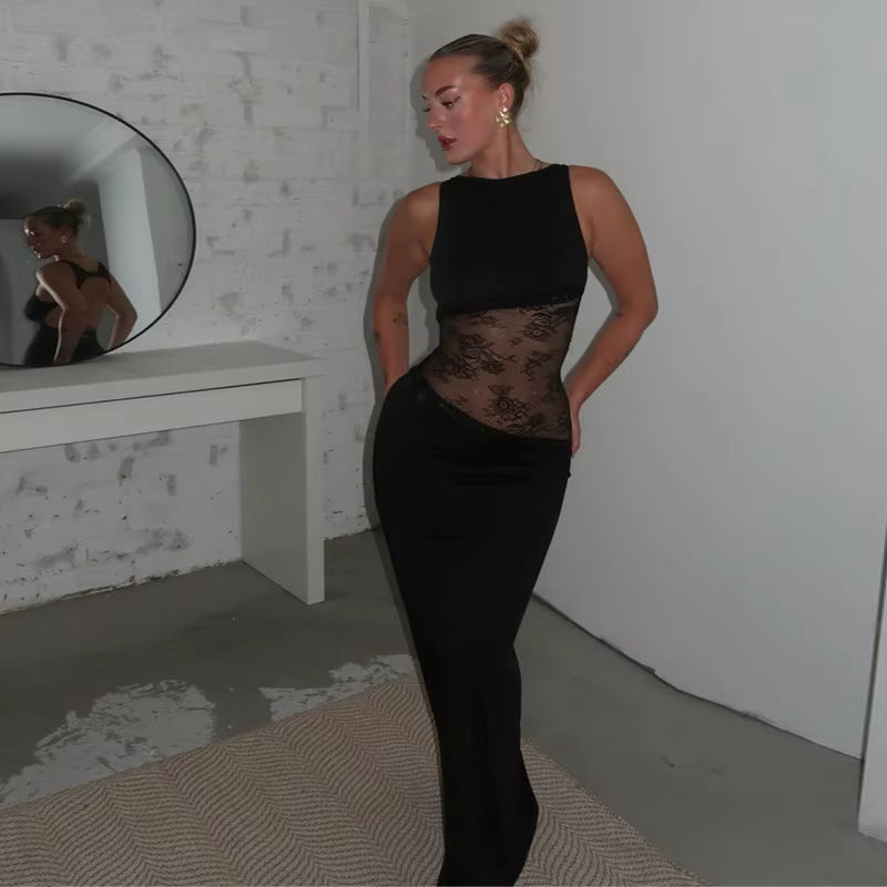 Woman wearing black gown with sheer lace bodice, standing in luxury hallway