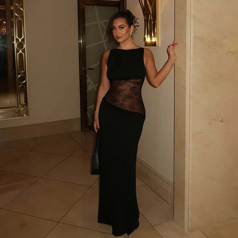 Woman wearing black gown with sheer lace bodice, standing in luxury hallway.